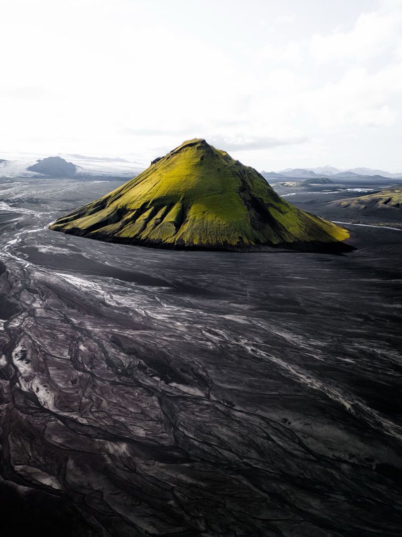 The moss-green cone of Mælifell rising from black sand plains