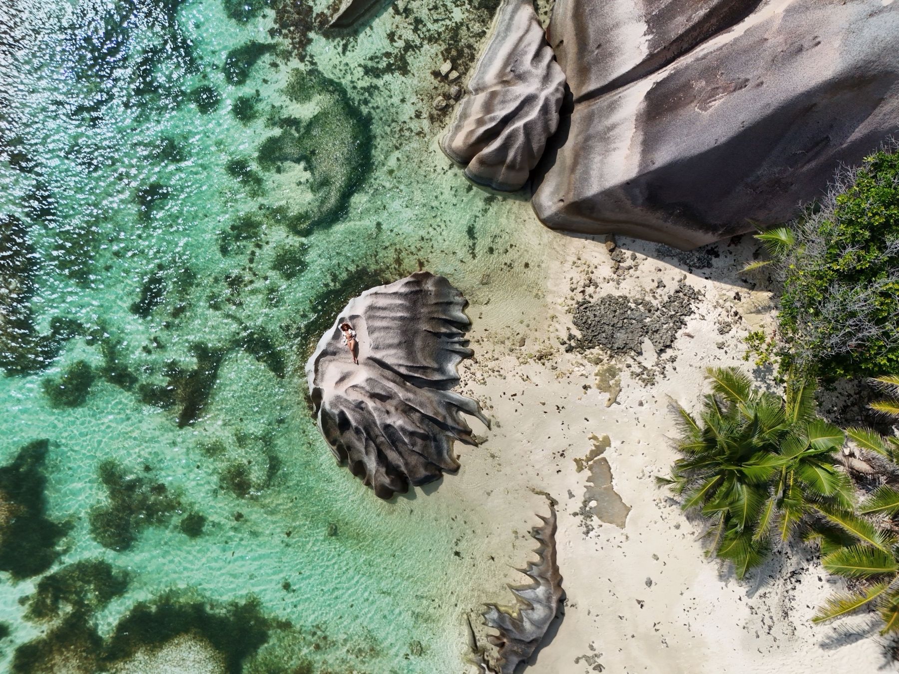 Aerial view of a sculpted granite boulder on a Seychelles beach