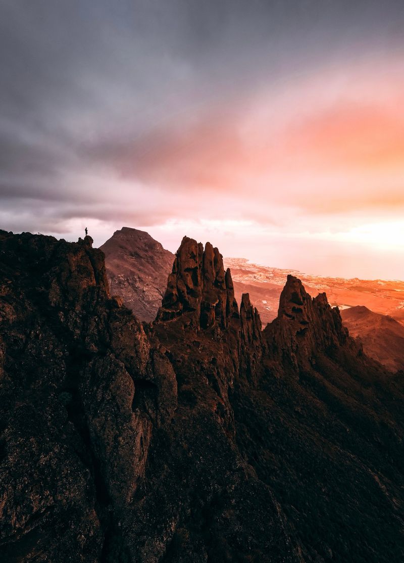 A hiker on a volcanic ridge above Tenerife at sunset